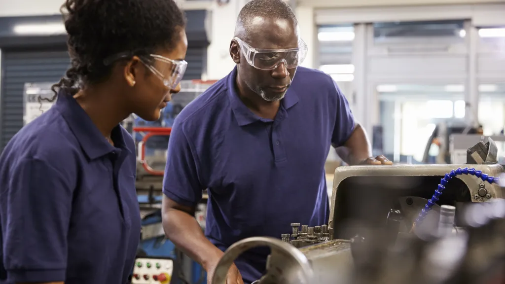 An engineer showing a student how to use a saw.